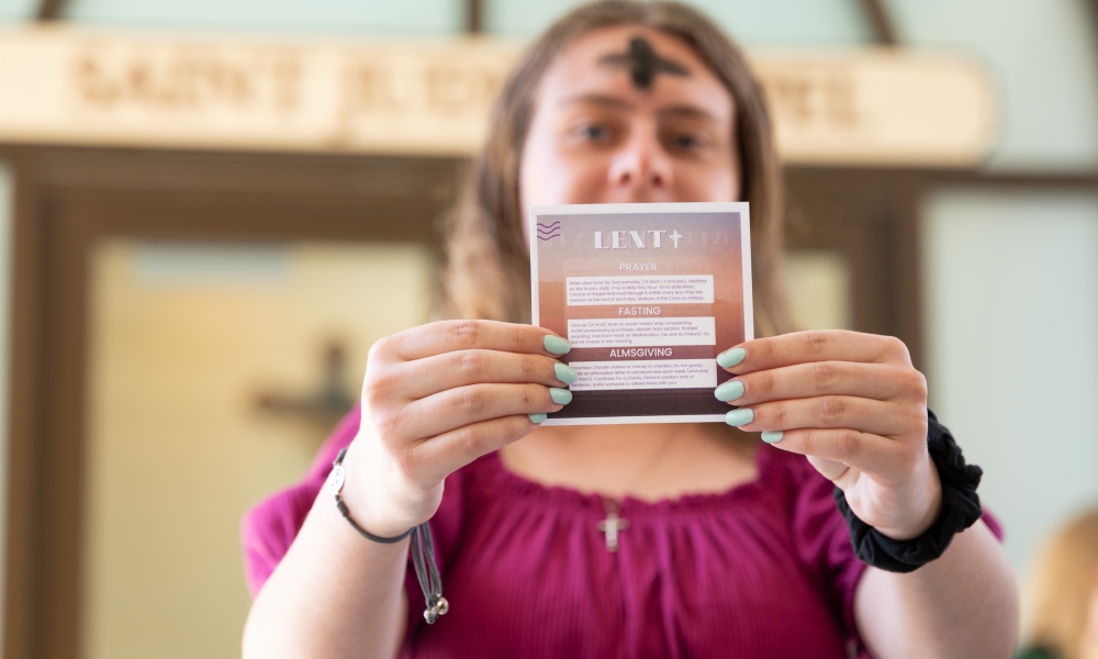 A Saint Leo University student holds a card showing the main tenets of Lent: prayer, fasting, and almsgiving, during a previous Ash Wednesday service at the university’s Pasco County campus.