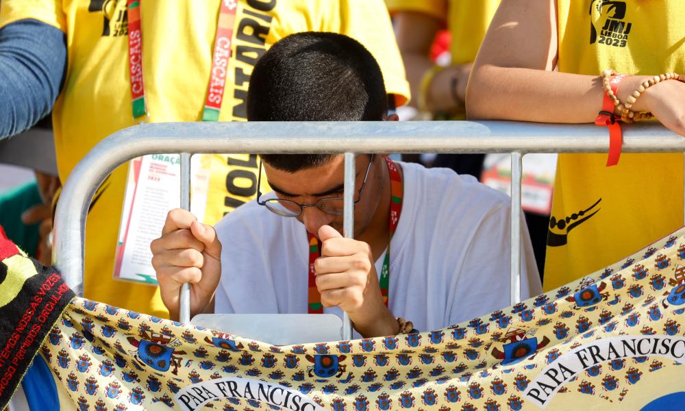 A young person prays while Pope Francis celebrates Mass for World Youth Day (CNS photo/Lola Gomez)