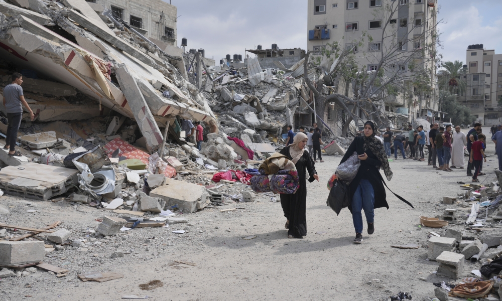 Palestinian women walk past destruction in Nuseirat camp in central Gaza.