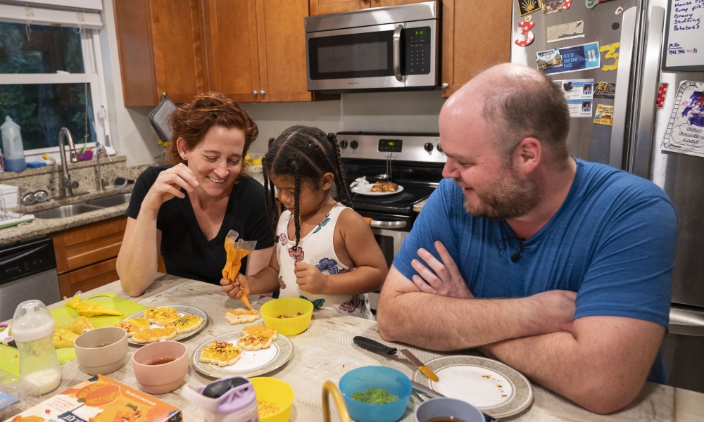 Dr. Stephen Okey, his wife Paige Cargioli, and their daughter Dorothy decorate cookies in their kitchen. Photo by Mary McCoy
