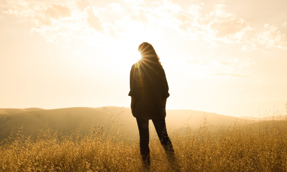 Silhouette of woman standing facing the sun