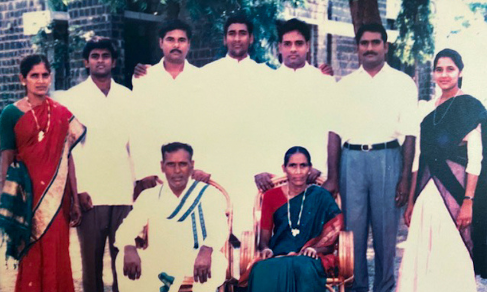 Joseph and Anna Mary Gangolu with their seven children around them, including Father Bob Romaine (fifth from left) and Father Bhaskar (fourth from left) in the center behind their parents.