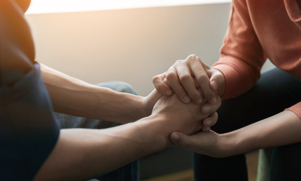 Two people holding hands in support