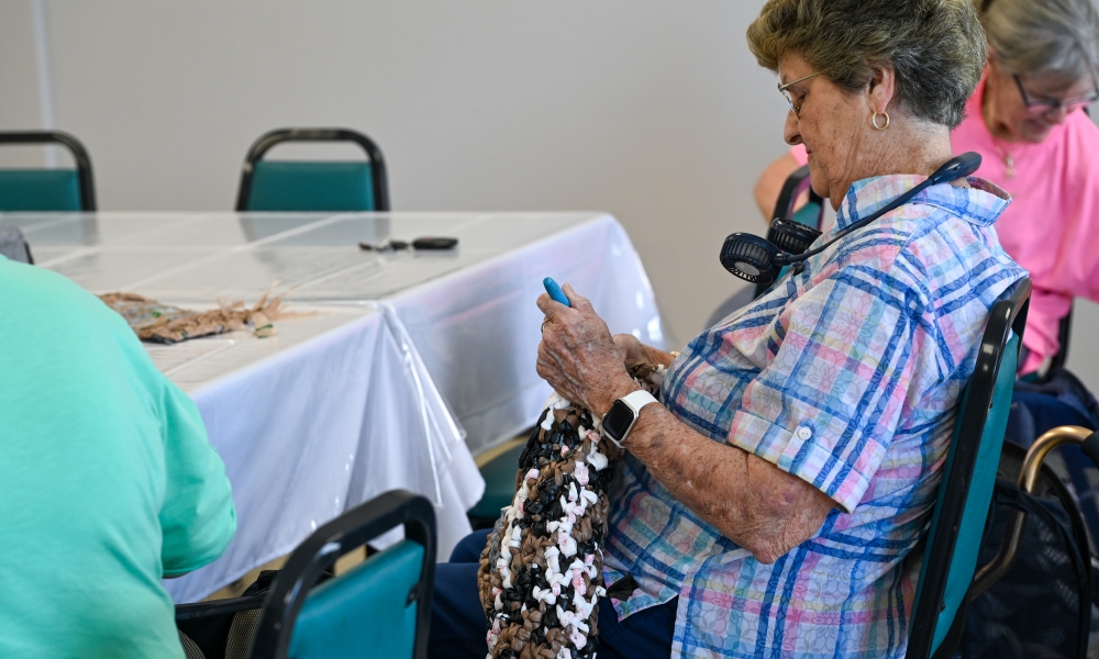 A woman crochets one of the mats for the homeless at Holy Cross Catholic Church. | Photo by Brittany DeHaan
