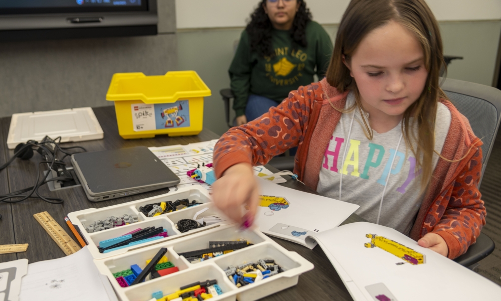 Reagan Kubasek looks at schematics for building her robot with camp assistant Jamin Torres, a sophomore robotics and artificial intelligence major, is ready to help.