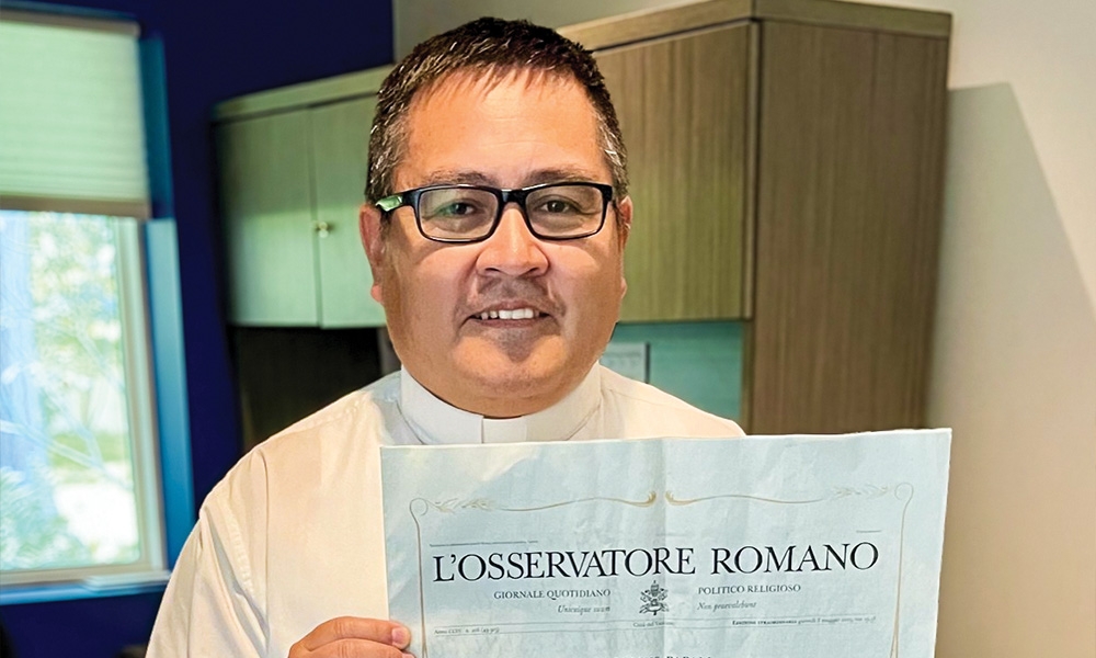 Father Amaro Ortiz holding a copy of L'Osservatore Romano