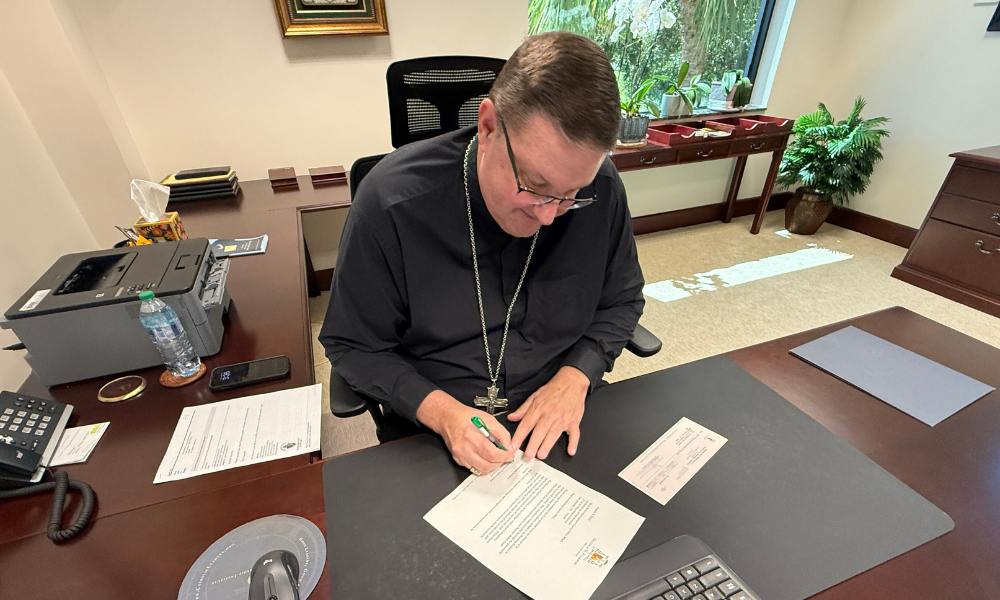 Bishop Parkes writes a letter to accompany a check to send to the Archdiocese of San Antonio to assist flood victims.