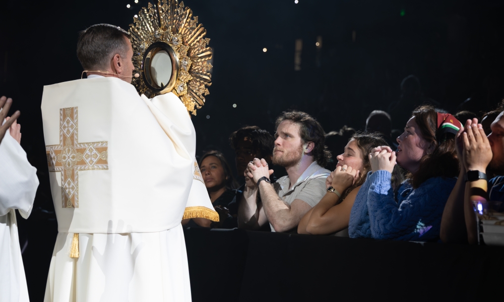 During the Eucharistic Encounter, Margaret Hynes, Ashley Jackson Hynes, and Danny Hynes pray as the monstrance is processed in front of them. | Photo by Keishla Espinal.