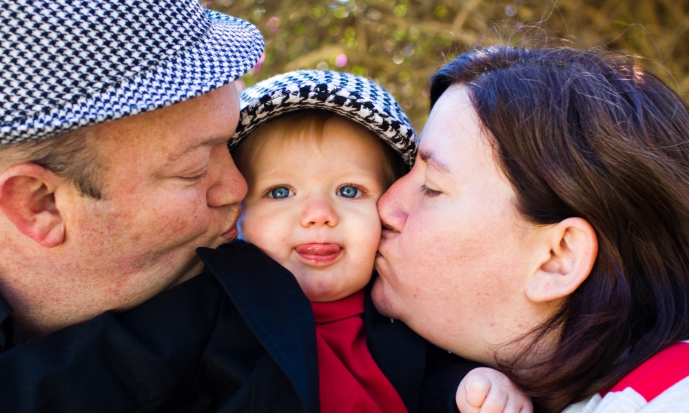 Couple kissing baby they adopted