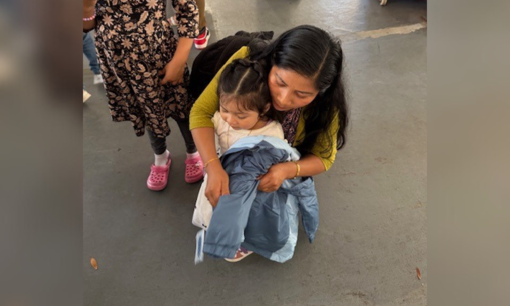 mom putting coat on child