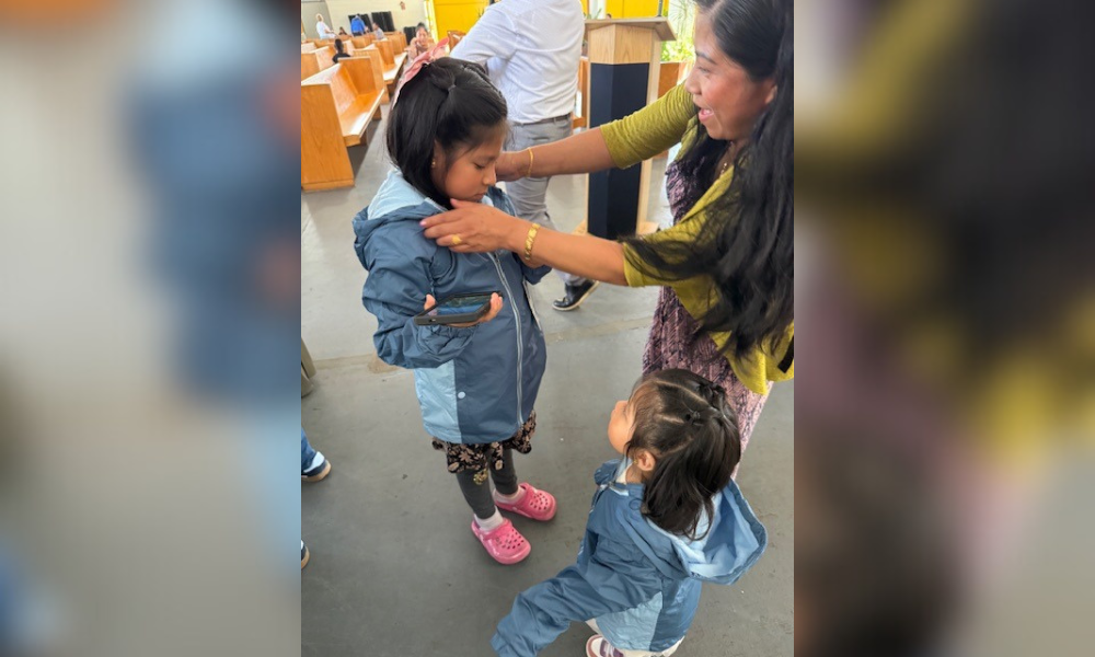 mom putting coat on child