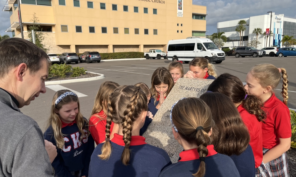 Students pray at one of the granite pillars for the martyrs