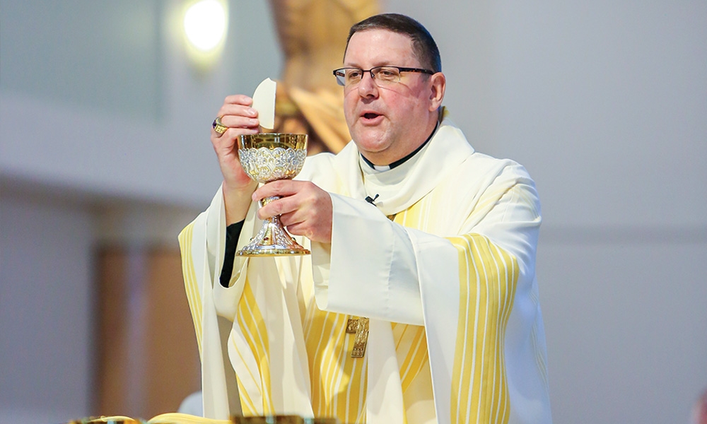 Bishop Gregory Parkes elevates the Body and Blood of Christ during the celebration of Mass at the Cathedral of St. Jude the Apostle