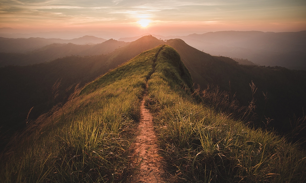 Pathway through mountains toward sunrise