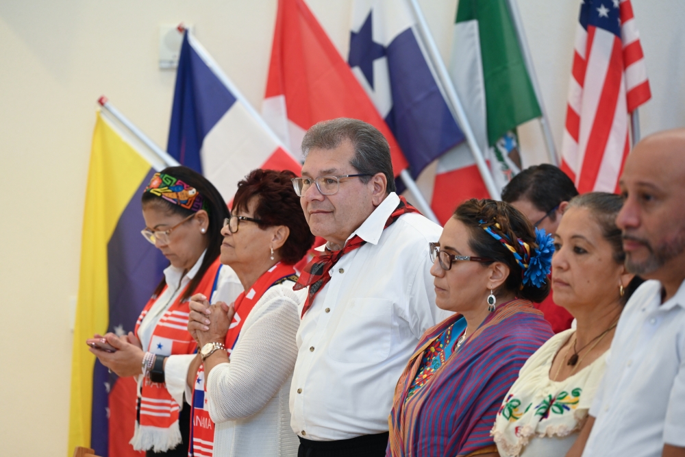 Miembros de la diócesis posan frente a banderas de diversos países durante la misa diocesana hispana. | Foto de Keishla Espinal.