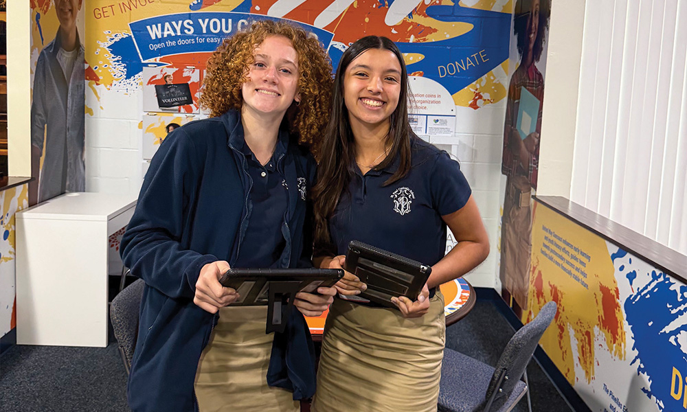 Olivia Grace standing beside with another school student, holding plaques