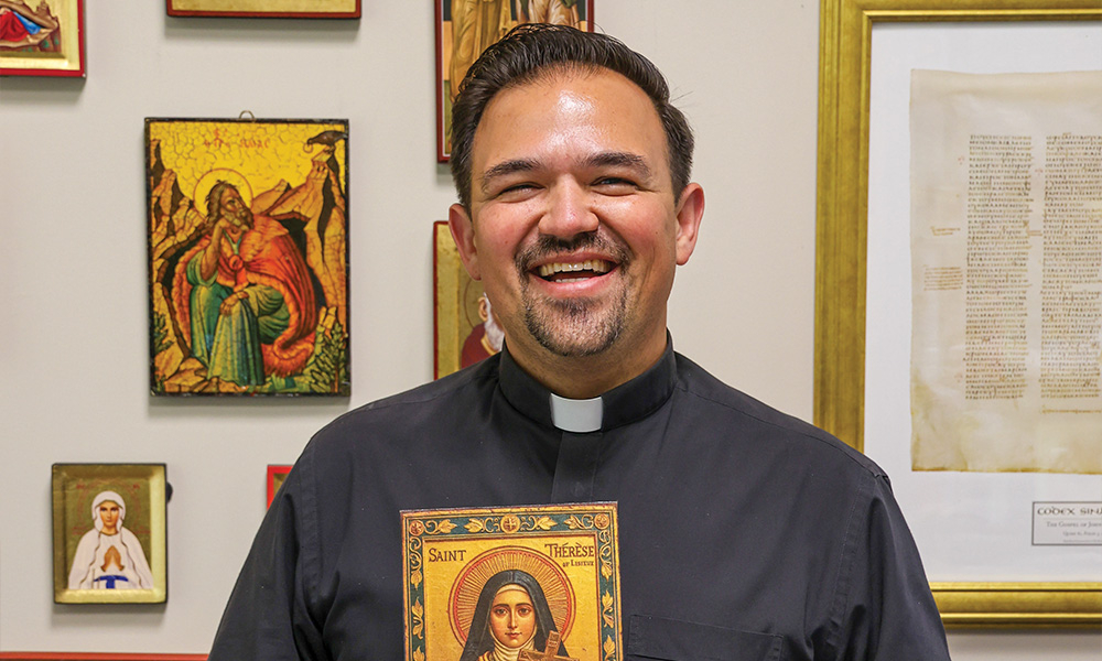 Father Xavy Castro holds an icon of St. Thérèse. He has many icons of beloved saints displayed on a wall in his office.
